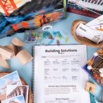 Lesson plan pages in a homeschool curriculum surrounded by picture books, vocabulary cards and wooden blocks,
