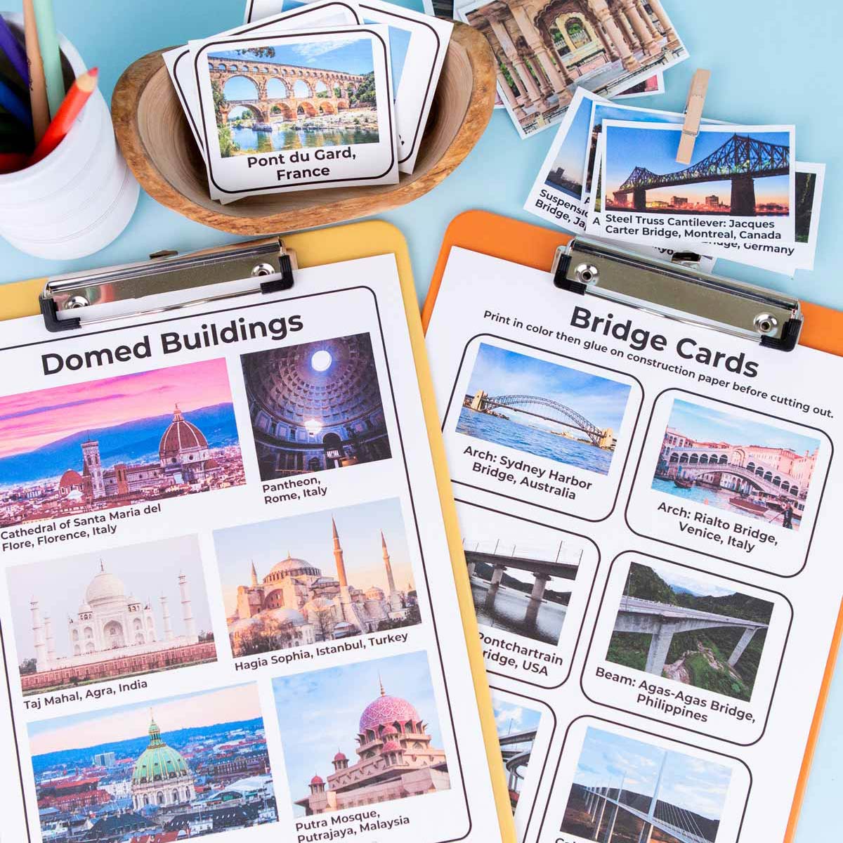 An overhead shot of printable cards - domed buildings and bridges. Some are cut out and others are hooked to a clipboard.